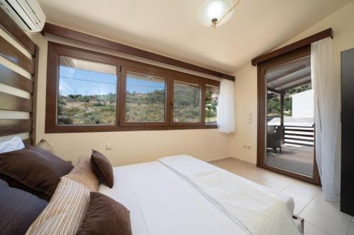 a bedroom with a white bed and a large window at Villa Kandia in Ayia Evfimia