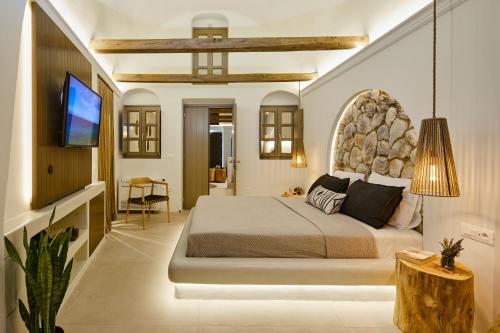 a bedroom with a large bed and a flat screen tv at Floria Suites in Karterados