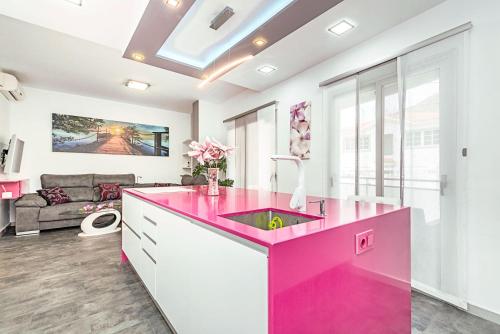 a pink kitchen with a sink and a living room at Sol Mogan Suites - Adults Only in Puerto de Mogán