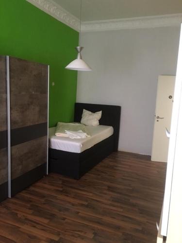 a small bedroom with a bed with a green wall at WOHNUNG IN KAISERSLAUTERN in Kaiserslautern