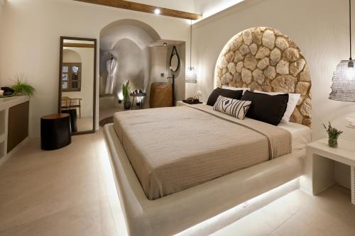 a bedroom with a large bed with a stone headboard at Floria Suites in Karterados
