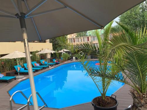 een zwembad met stoelen en een parasol en een palmboom bij Richmond Hotel in Mamaia