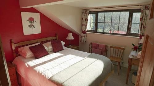 Llanwrtyd WellsにあるKilsby Cottageの赤い壁のベッドルーム1室(大型ベッド1台付)