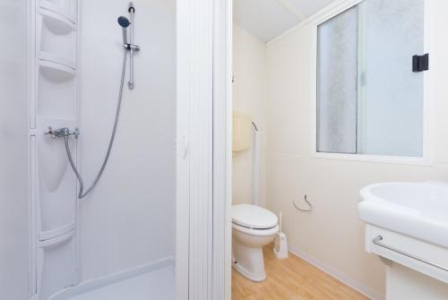 biała łazienka z toaletą i prysznicem w obiekcie Camping Adria Mobile Homes in Brioni Sunny Camping w Puli