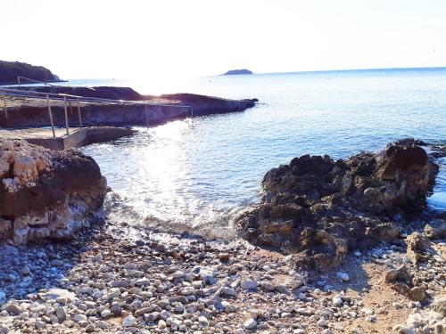 a rocky beach with a pier and the water at Apartment Complex Jelena in Funtana