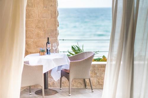 a table with a bottle of wine on a balcony with the ocean at Plaza Hotel&SPA in Ulcinj