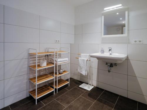 a white bathroom with a sink and a mirror at Travel Art Boardinghouse in Neuruppin