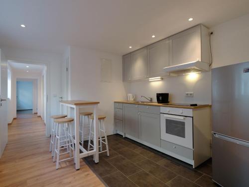 a kitchen with white cabinets and a table and stools at Travel Art Boardinghouse in Neuruppin