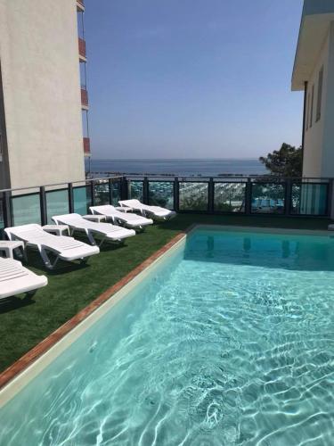 a swimming pool with chaise lounges and chairs on a building at Hotel Mirage in Lido di Classe