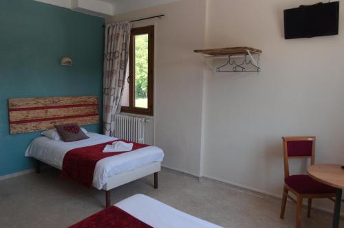 a bedroom with a bed and a table and a window at Ô & Cimes in Saint-Pierre-dʼAlbigny