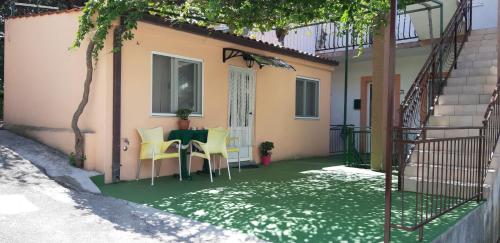 een patio met een tafel en stoelen op een groene verdieping bij Apartman Gabriel in Podgora
