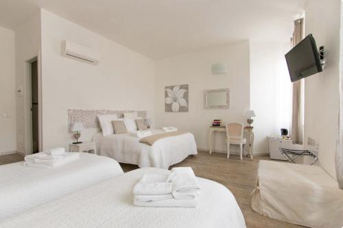 a white room with two beds and a tv at Affittacamere Casa Dane' in La Spezia