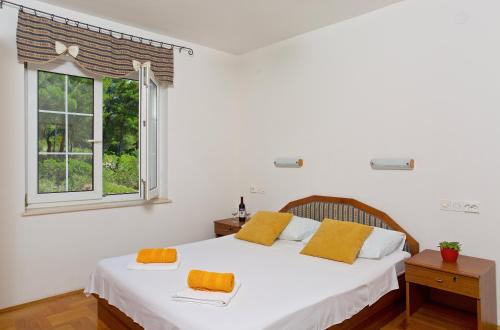 a white bedroom with a large bed with yellow pillows at Apartments Kalina in Jelsa