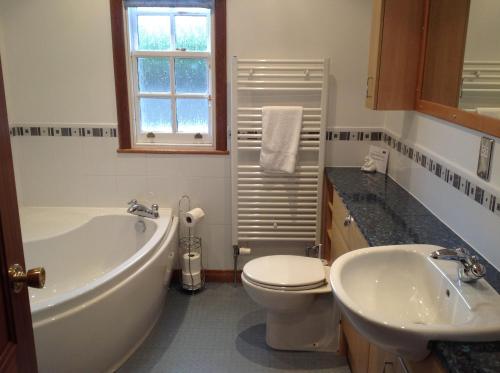 ein Badezimmer mit einer Badewanne, einem WC und einem Waschbecken in der Unterkunft The Towerview Coach Houses in Perth