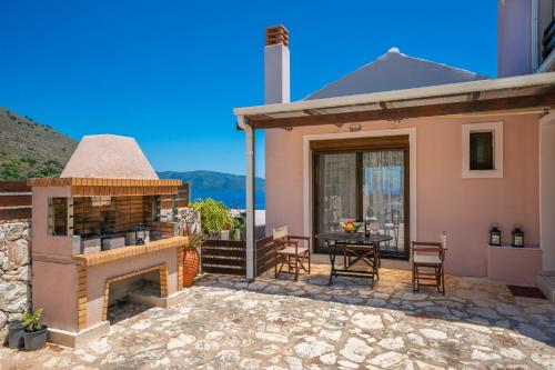 a house with a patio with a fireplace and a table at Villa Kandia in Ayia Evfimia