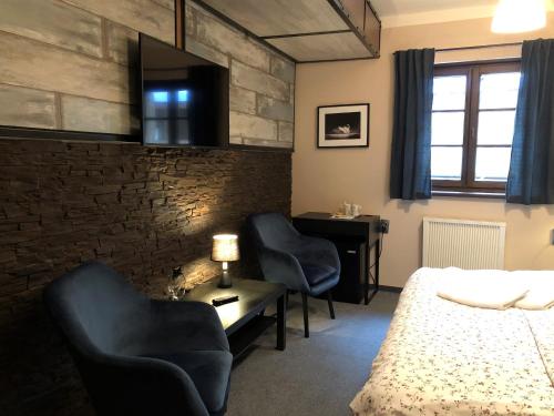 a bedroom with two chairs and a bed and a desk at Kazmarka in Malá Morávka
