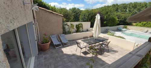 une terrasse avec une table, un parasol et une piscine dans l'établissement LES PRAIRIES DE L'ENCREME, à Céreste