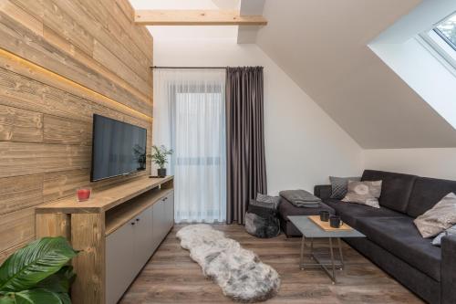a living room with a couch and a tv at Hotel Královka in Bedřichov