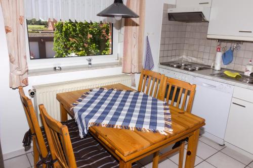 a kitchen with a wooden table with a checkered table cloth on it at FeWo Heitkamp in Dornumersiel