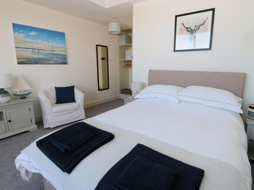 ein Schlafzimmer mit einem großen weißen Bett und einem Stuhl in der Unterkunft Rosemary Cottage in Chathill