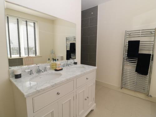 ein Badezimmer mit Waschbecken und großem Spiegel in der Unterkunft Rosemary Cottage in Chathill