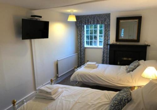 a hotel room with two beds and a television at The Dorset Arms Pub & Cottage Rooms in Groombridge