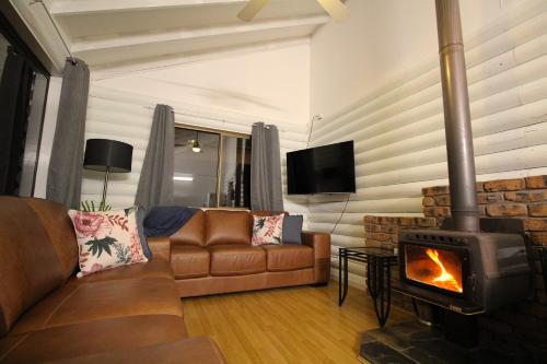 a living room with a couch and a fireplace at Palmers Lane Estate Hunter Valley in Pokolbin