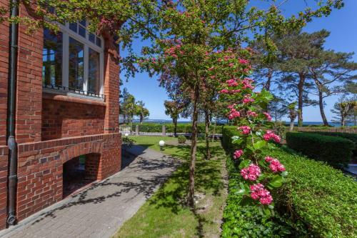奧茨巴德賓茲的住宿－Villa Glueckspilz KILIG mit Meerbl，砖屋,有粉红色的花和窗户