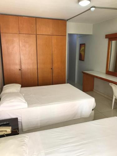 a bedroom with two beds and a desk and cabinets at Garvey Flats in Brasilia