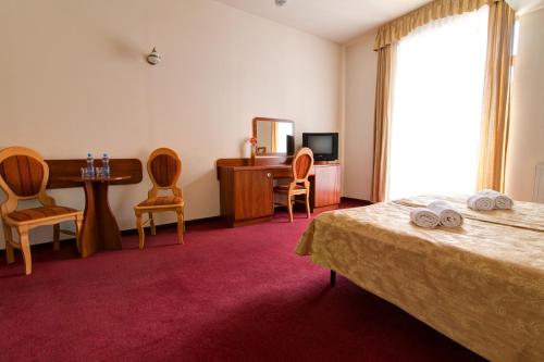 a hotel room with a bed and a desk and chairs at Apartamenty Renesans in Krynica Zdrój