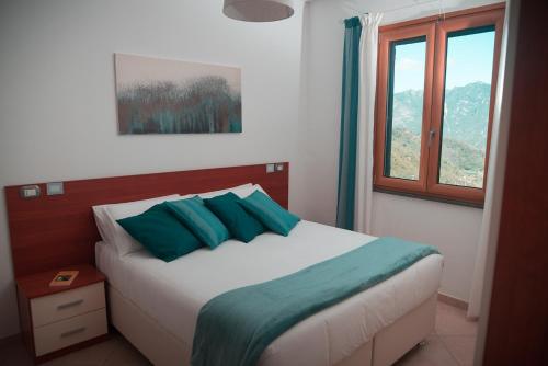 a bedroom with a bed with blue pillows and a window at Nonna Carmelina in Ravello