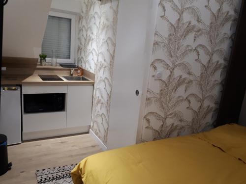 Cette chambre comprend une petite cuisine avec un lit jaune. dans l'établissement L'Essentiel, studio cosy, quartier Anatole France, CHU, à Rennes
