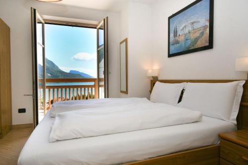a large white bed in a room with a window at Residenza Alba - Molveno in Molveno