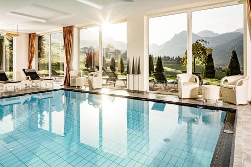 una piscina con sedie e vista sulle montagne di Bella Vista Hotel Emma a San Vigilio Di Marebbe