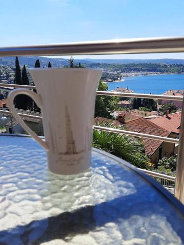 a white coffee cup sitting on a table with a view at Red Rose Apartment in Portorož