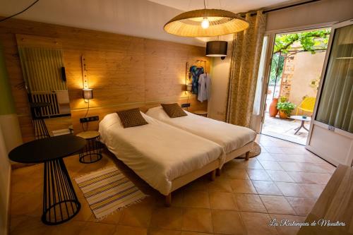 a bedroom with a large bed and a table at Hotel Les Restanques De Moustiers in Moustiers-Sainte-Marie