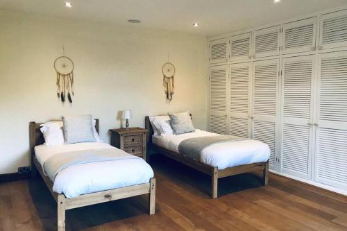 two beds in a room with white walls and windows at Bretton House Farm Retreat in Chester