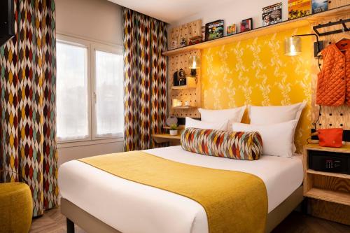 a hotel room with a bed and a yellow wall at Hotel Locomo - Gare de Lyon Bastille in Paris
