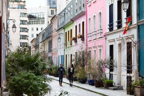 two people walking down a street with colorful buildings at Hotel Locomo - Gare de Lyon Bastille in Paris