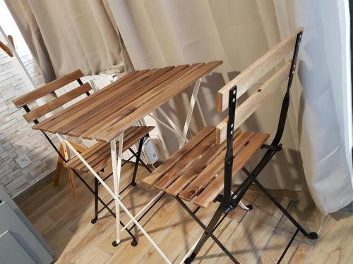une table en bois et deux chaises à côté d'une table dans l'établissement SW Cosy Studio - Chambly Persan Roissy CDG, à Persan