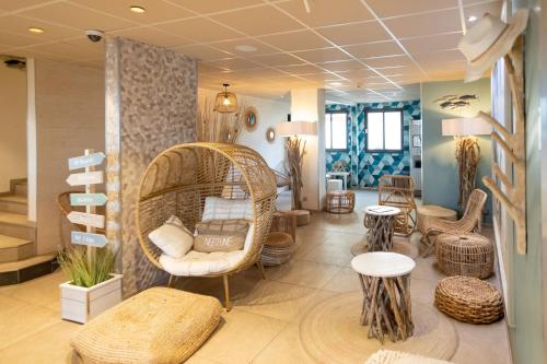 a room with a wicker chair and some tables and chairs at The Originals Boutique, Hôtel Neptune, Berck-sur-Mer in Berck-sur-Mer