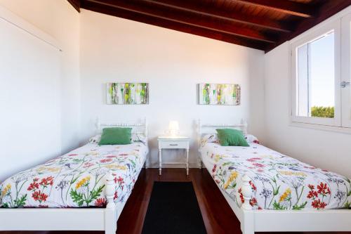 ロス・レアレホスにあるSan Benito - Vivienda vacacionalの白い壁と窓が備わる客室で、ベッド2台が備わります。