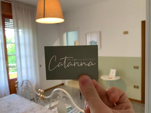 a person holding up a sign that says calima at B&B Catarina in Tollo