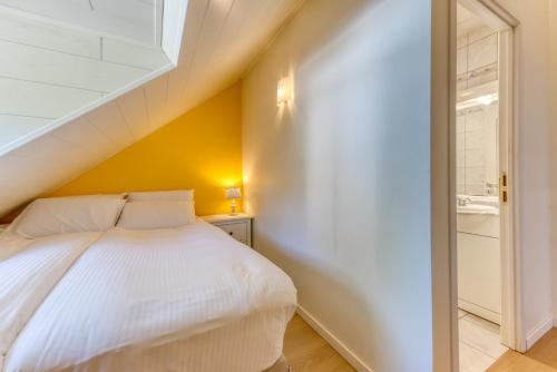 a bedroom with a white bed and a yellow wall at Le Domaine de Wisbeley in Halet