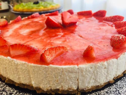 a strawberry cheesecake with strawberries on top on a table at Hotel Cimarosa in Riccione