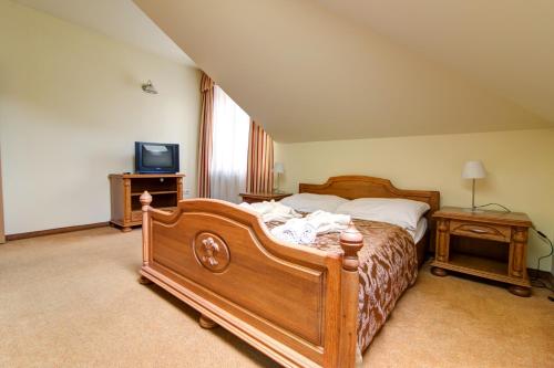 a bedroom with a wooden bed and a tv at Apartamenty Renesans in Krynica Zdrój