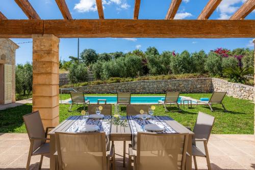 an outdoor dining area with a table and chairs and a pool at Can Bosco in Son Servera