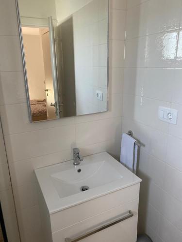 a white bathroom with a sink and a mirror at Apartmani Bella Vista in Njivice