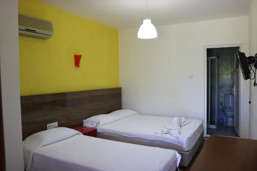 a hotel room with two beds and a lamp at Simge Pension in Cıralı