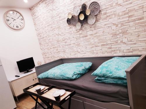 ein Zimmer mit einem Sofa mit Kissen und einer Ziegelwand in der Unterkunft SW Cosy Studio - Chambly Persan Roissy CDG in Persan